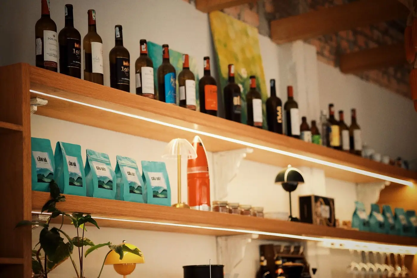A warm cafe shelf with bottles and bags of coffee