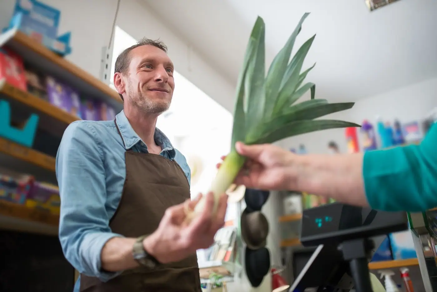 Friendly clerk helping a customer choose vegetables at a grocery counter