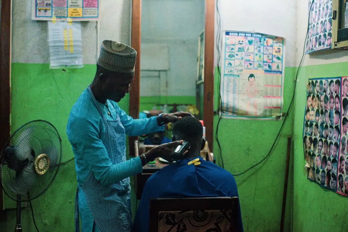 Barber using clippers to cut hair in a vintage barbershop setting