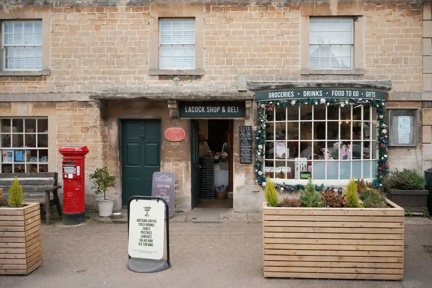 A village shop and deli front in Lacock, England, offering groceries and more.