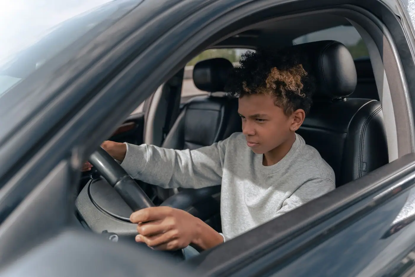 A teenager learning to drive a car, focused and determined.