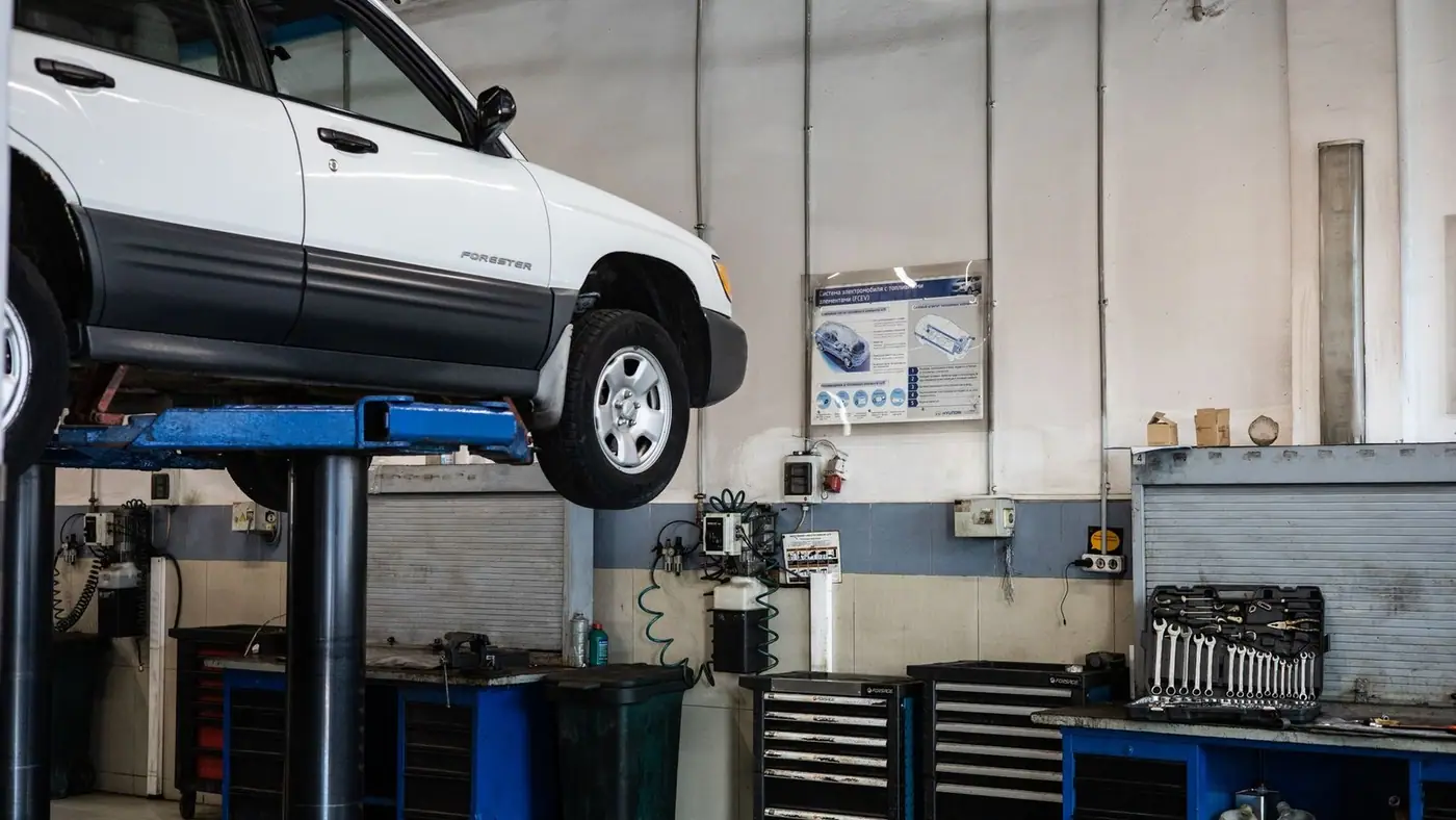A car is elevated on a lift in a modern automotive repair shop, showcasing tools and equipment.