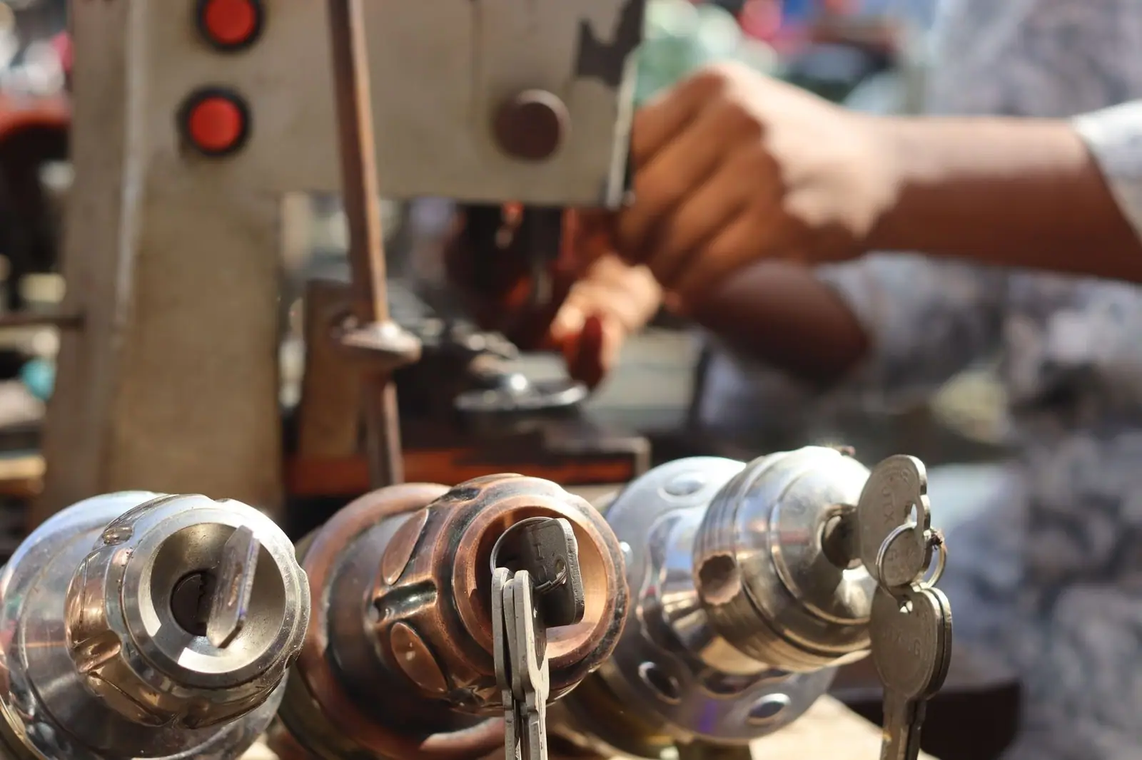 Close-up image of locksmith tools and hands working with a key machine outdoors