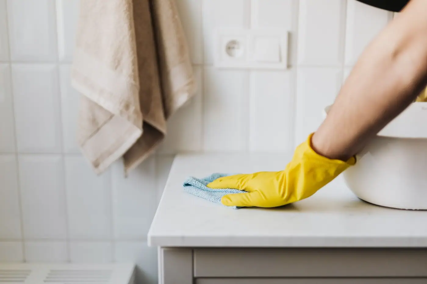 Anonymous woman in yellow protective gloves cleaning a surface