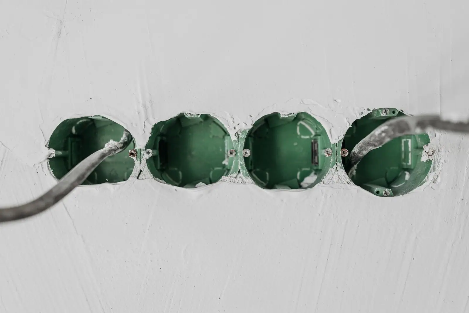 Close-up of green electrical boxes and wiring in a wall setup