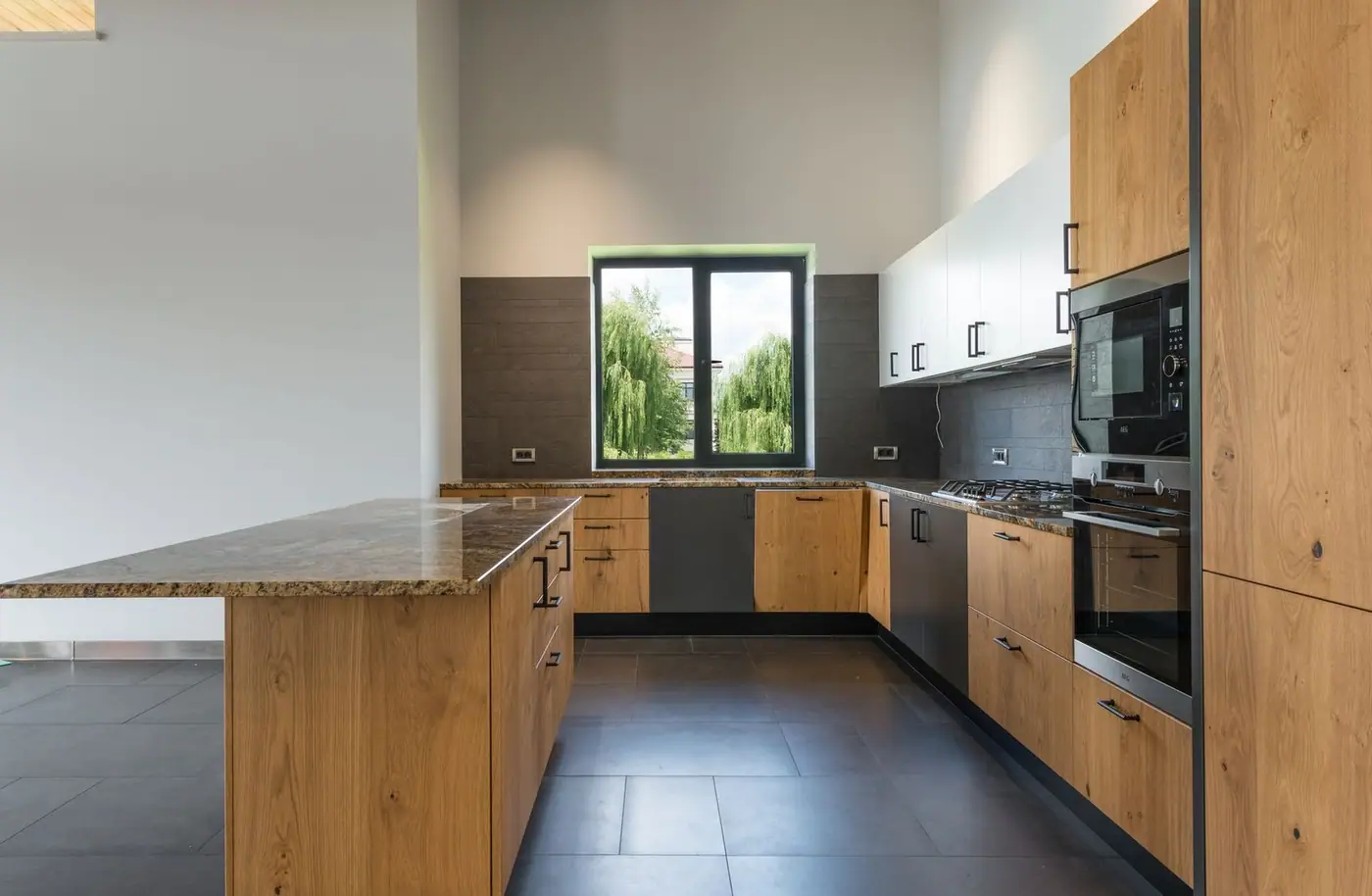 Spacious kitchen with a wooden counter in the middle, built-in stove and many cabinets