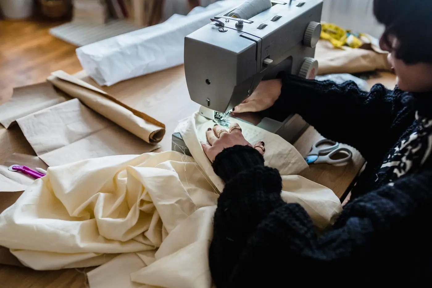 From above, a sewer stitching fabric with a sewing machine