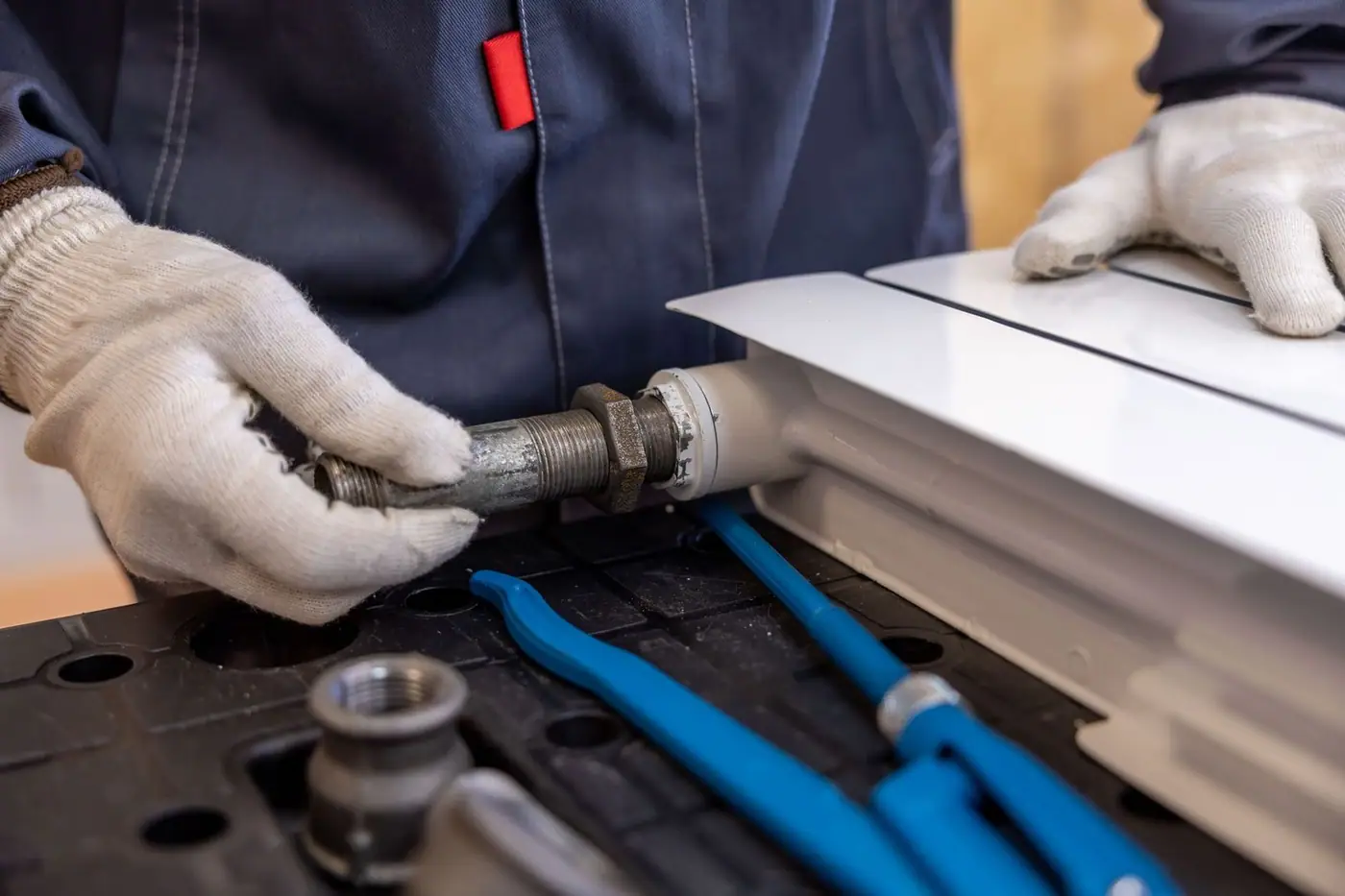 Close-up of a plumber installing a radiator pipe using specialised tools