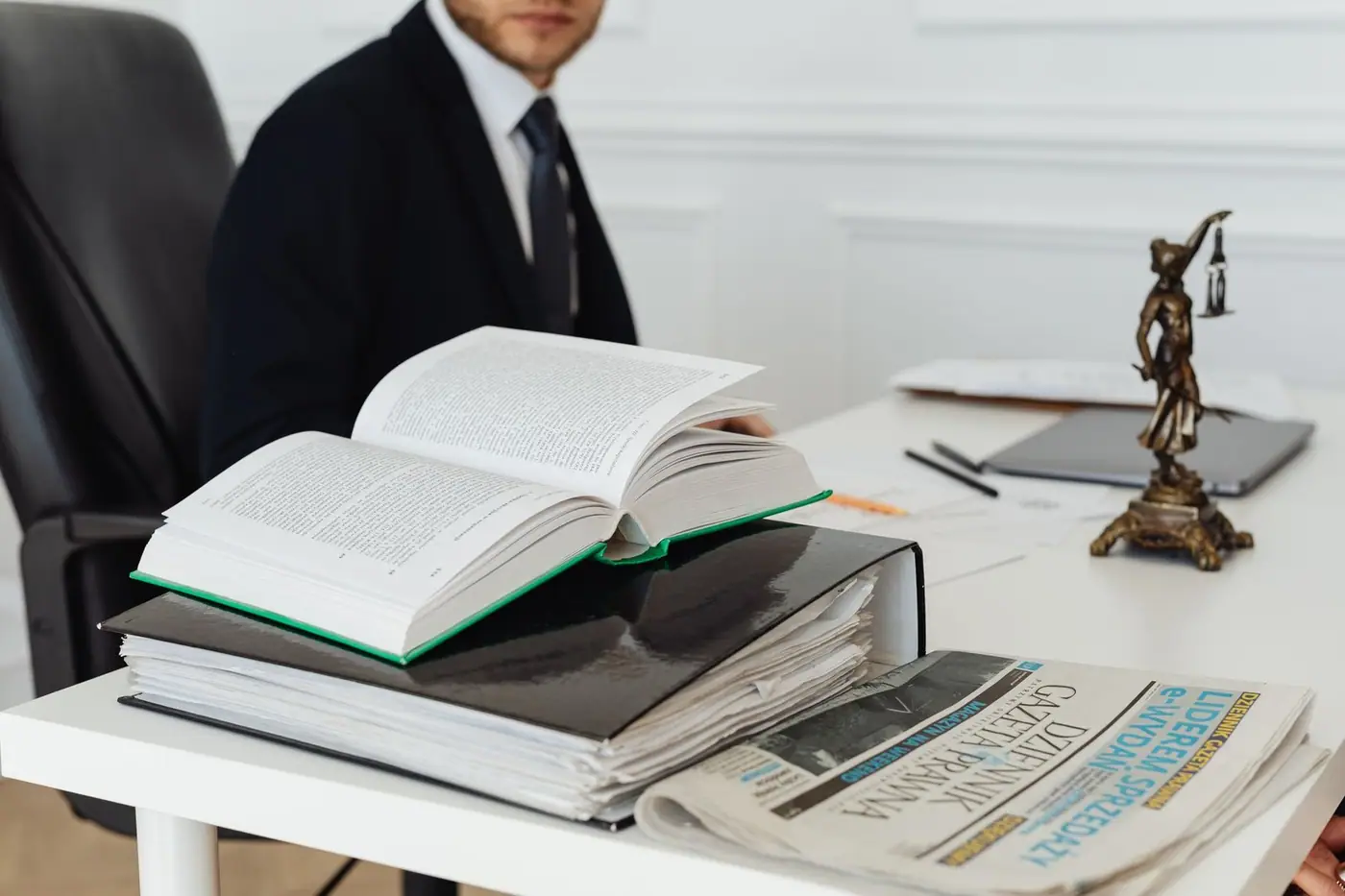 A lawyer sitting at a desk with legal books, documents and a newspaper