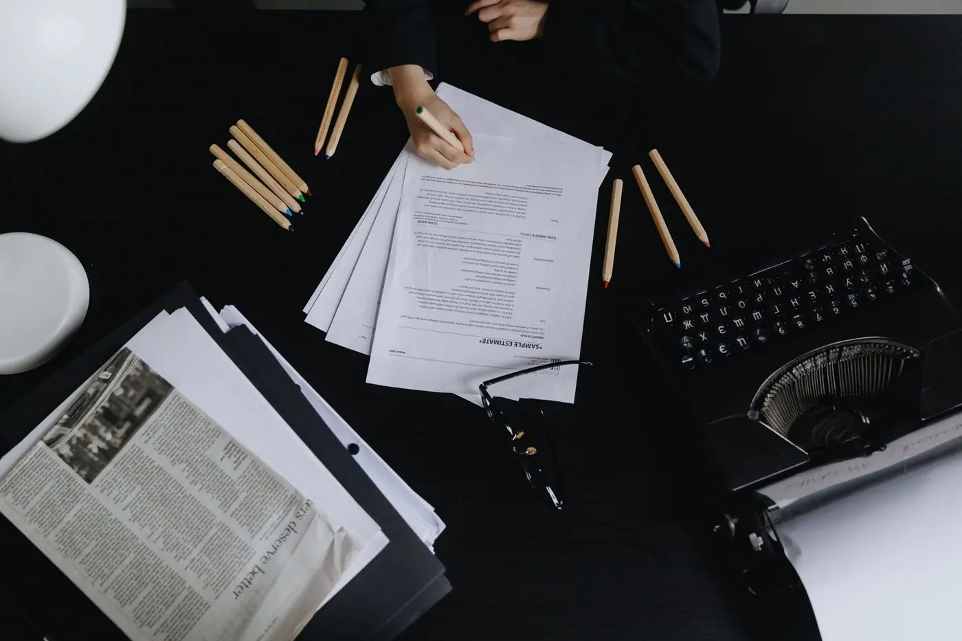 Aerial view of a desk with papers, a typewriter and coloured pencils