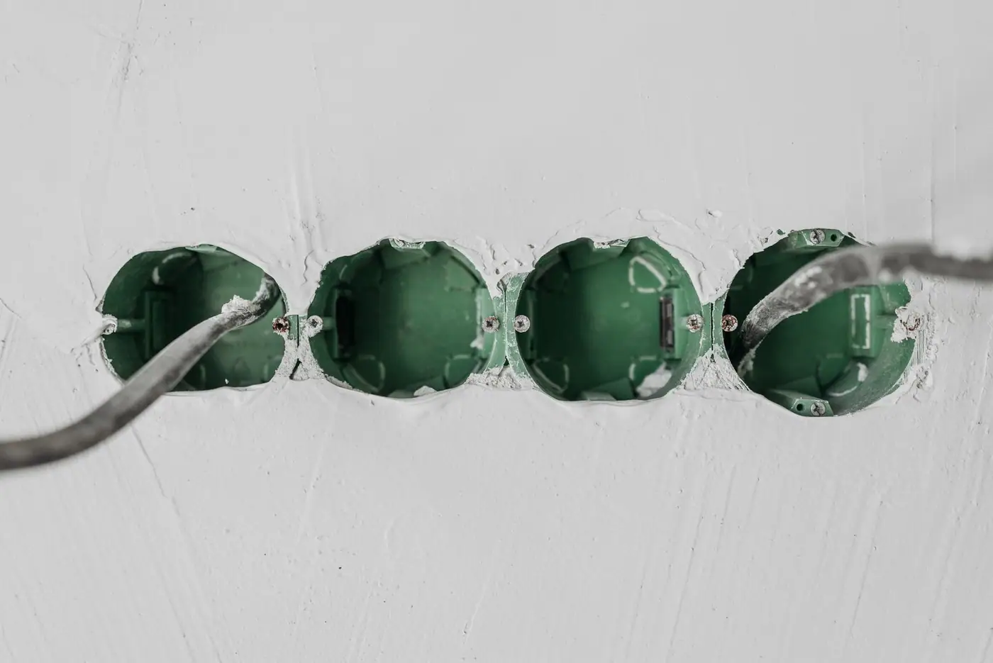 Close-up of green electrical boxes and wiring in a wall