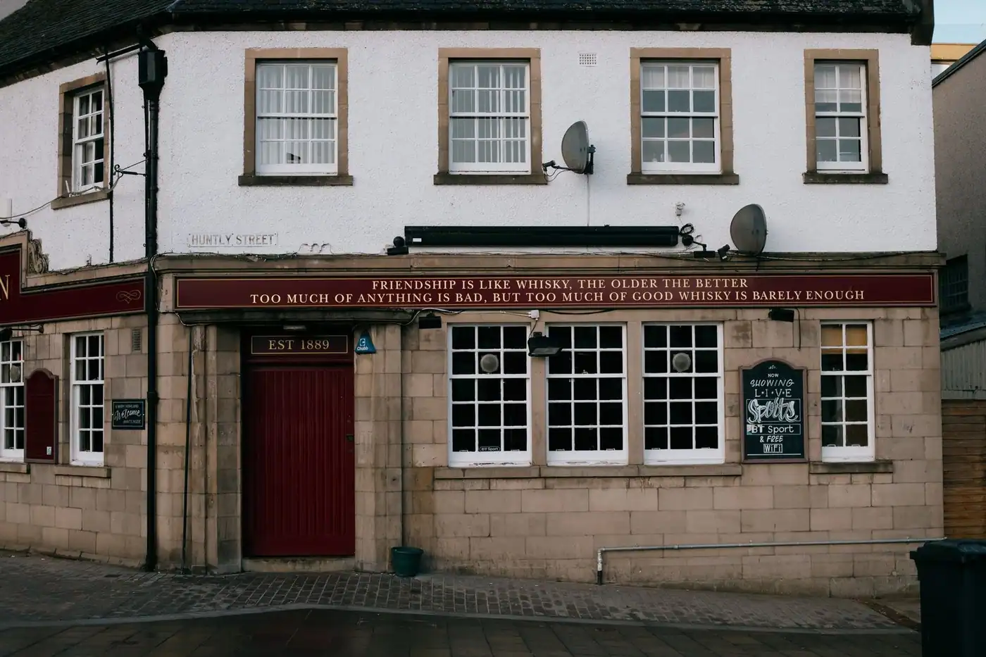 Exterior of a bar in Inverness with a whisky-related quote on the wall