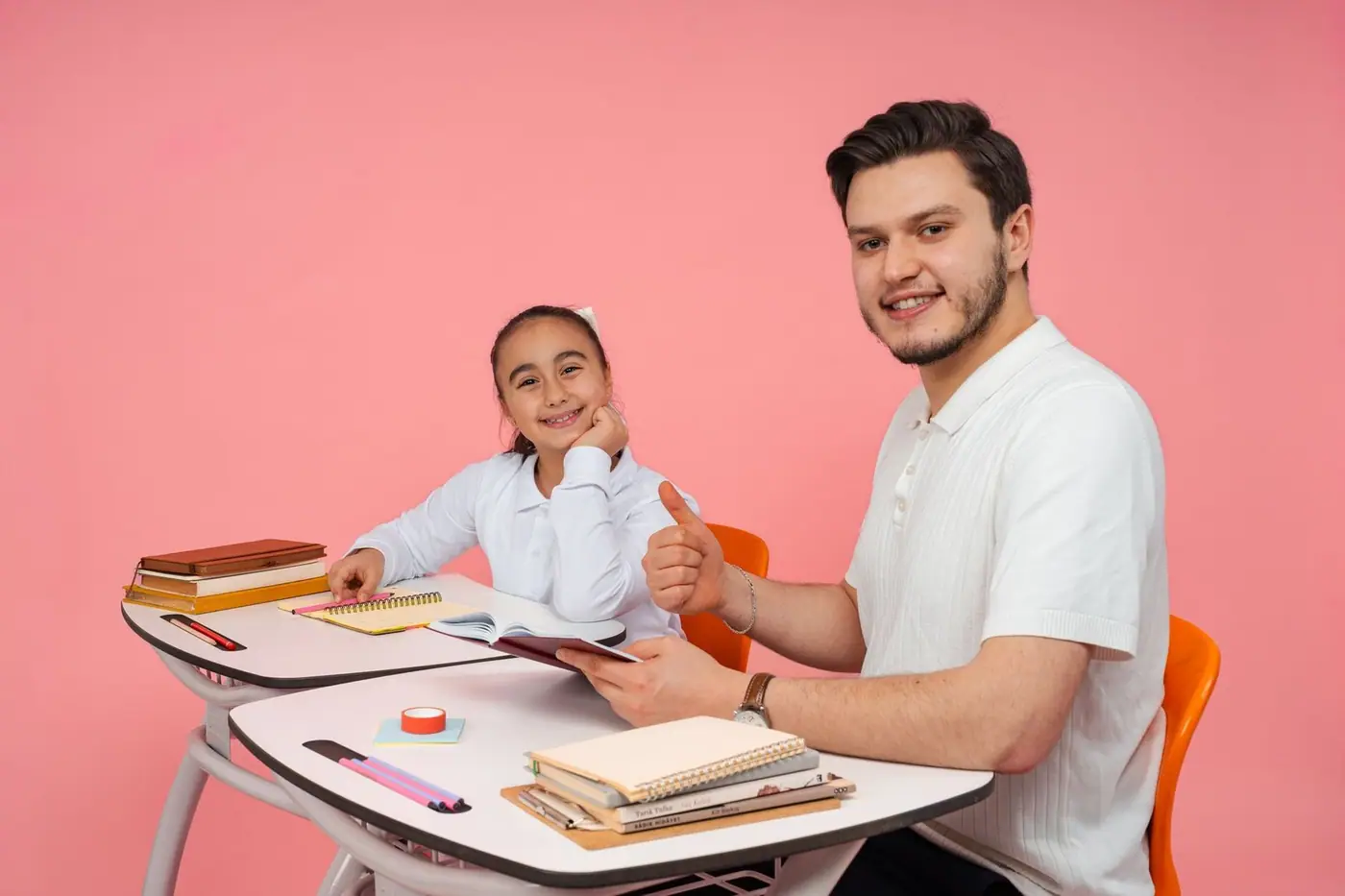 A teacher and a student smiling together at a desk in a classroom