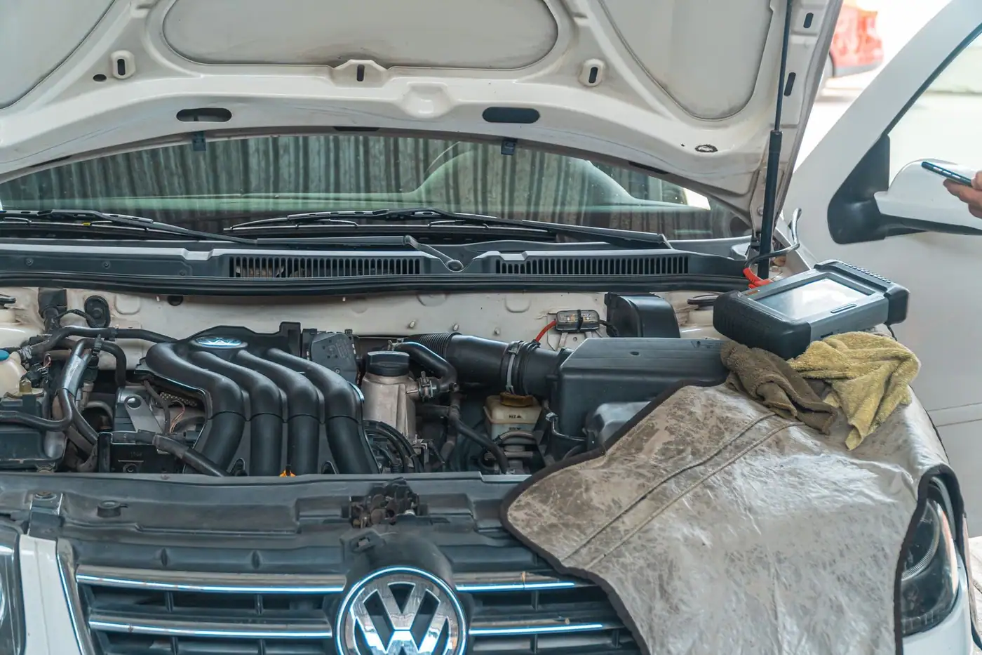 Close-up of a car engine undergoing repair in a garage, with tools and diagnostic equipment in use.