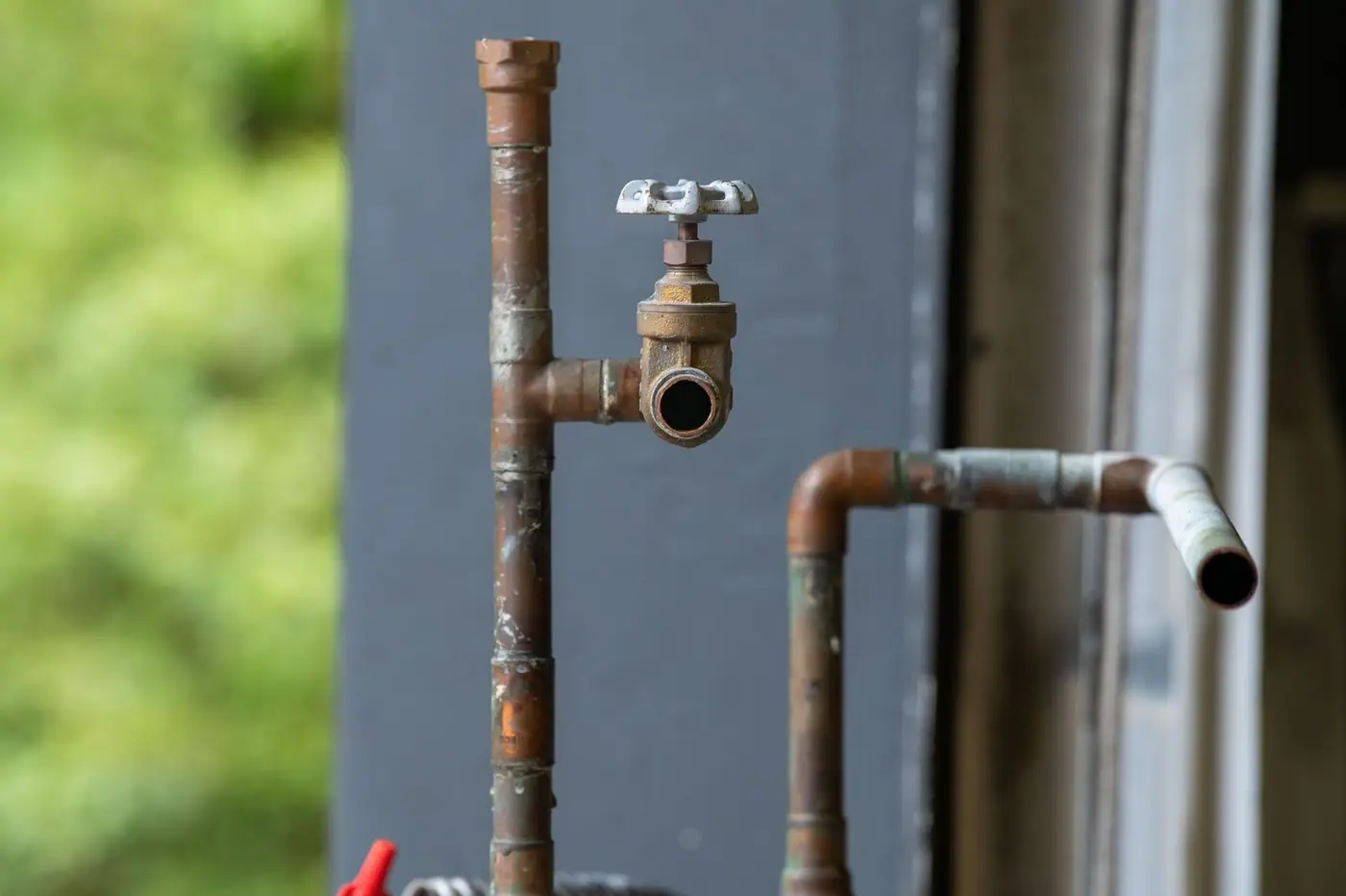 Close-up of an old, rusty industrial water pipe with a valve