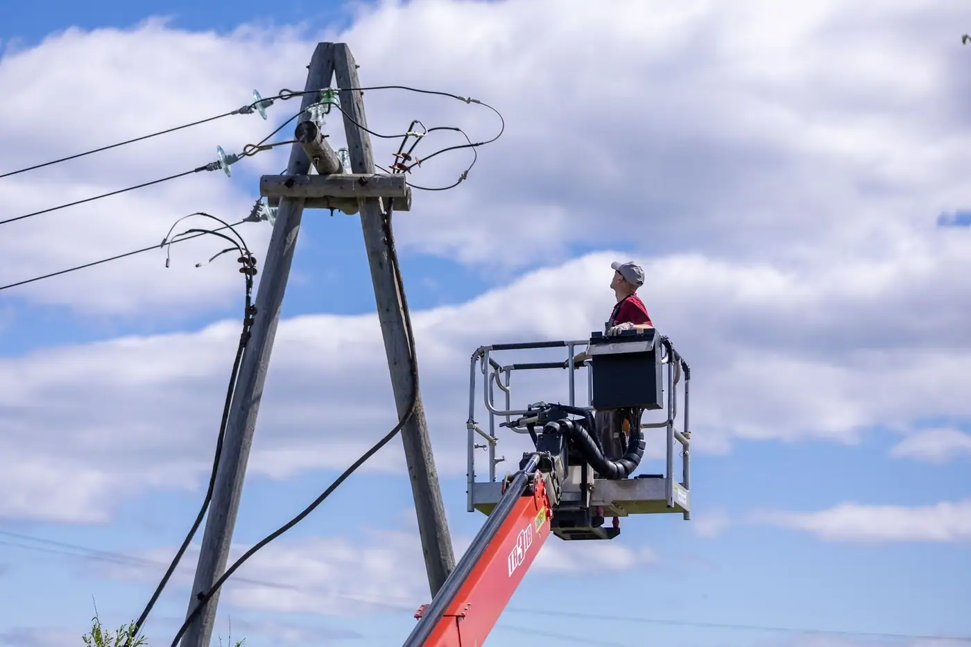 Worker on a hydraulic lift repairing power lines on a clear day