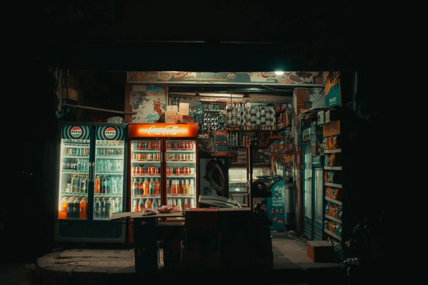 A cosy convenience store with illuminated drinks coolers at night