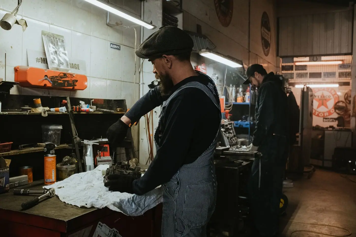 Two auto mechanics working on a vehicle in a dimly lit garage