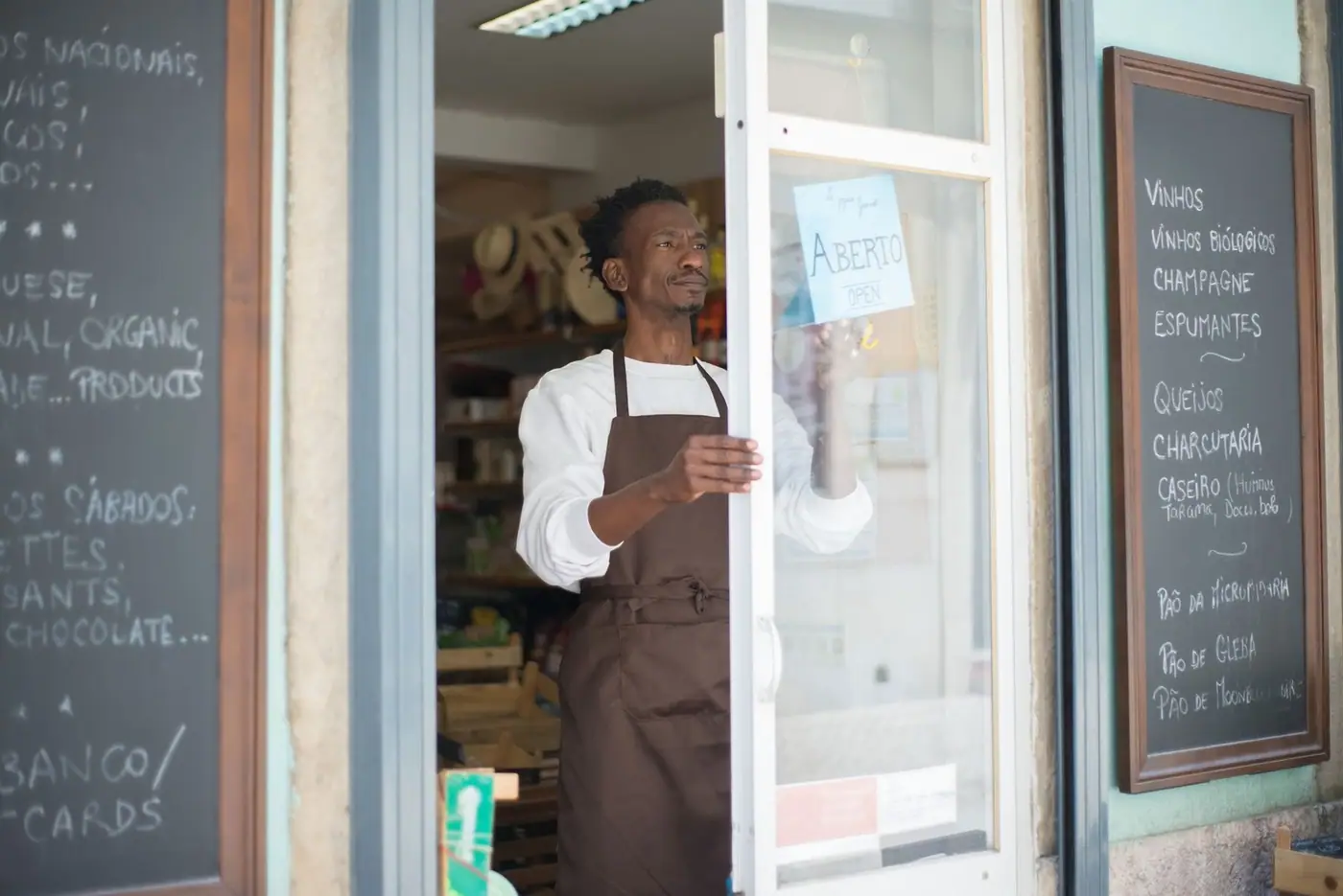 A man in an apron opening a shop door, ready for business