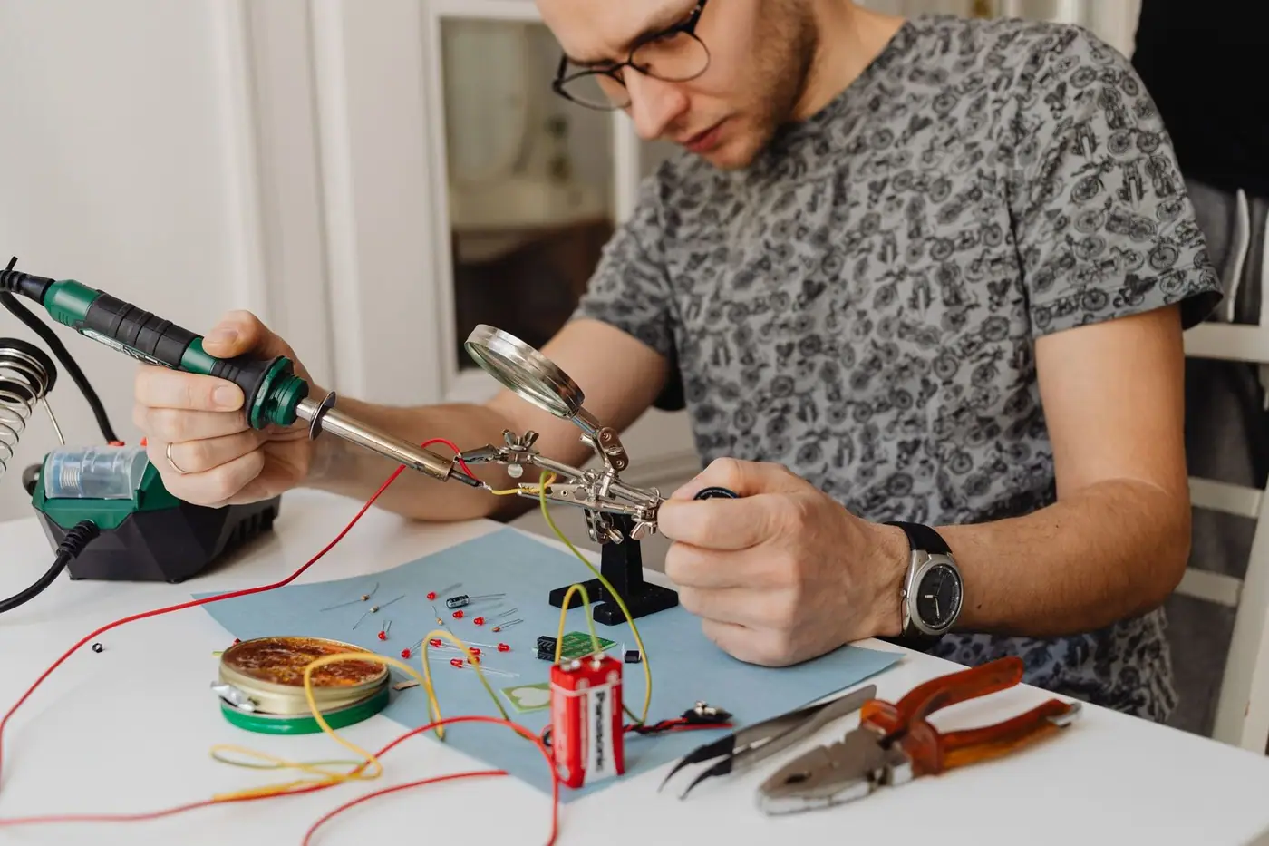 A technician soldering electronics with precision tools at an indoor workbench
