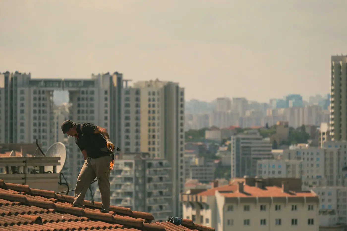 Construction worker on a rooftop with a city skyline in the background