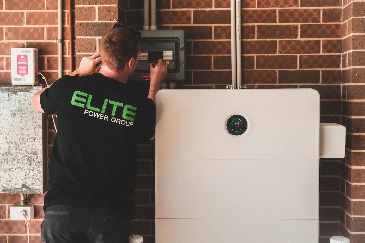Electrician installing a home energy battery storage unit in a house