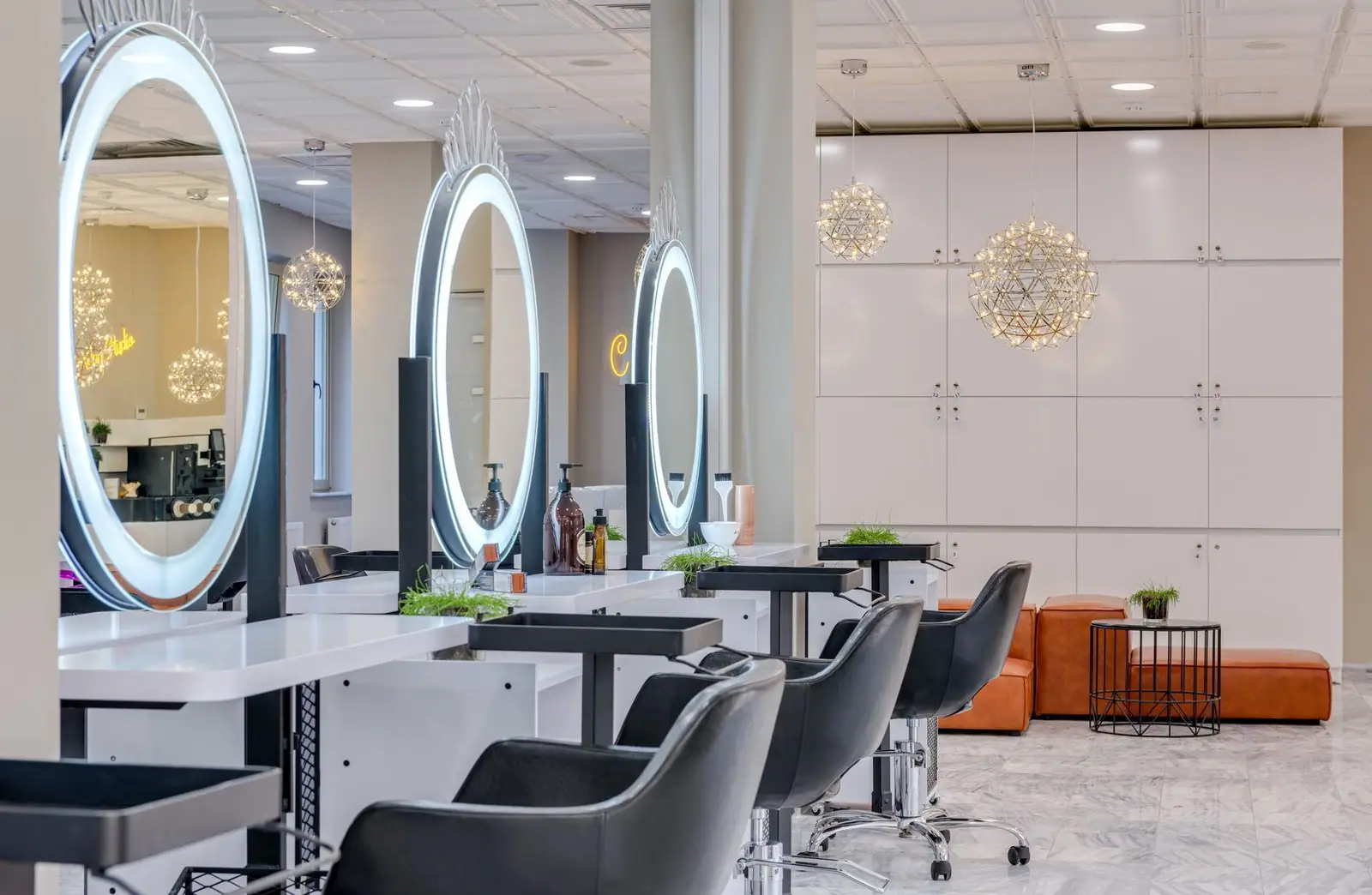 Bright and elegant hair salon interior featuring modern lighting and round mirrors for a chic and relaxing atmosphere.
