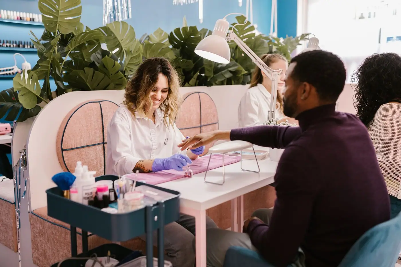 A man getting a professional manicure in a stylish, vibrant nail salon setting