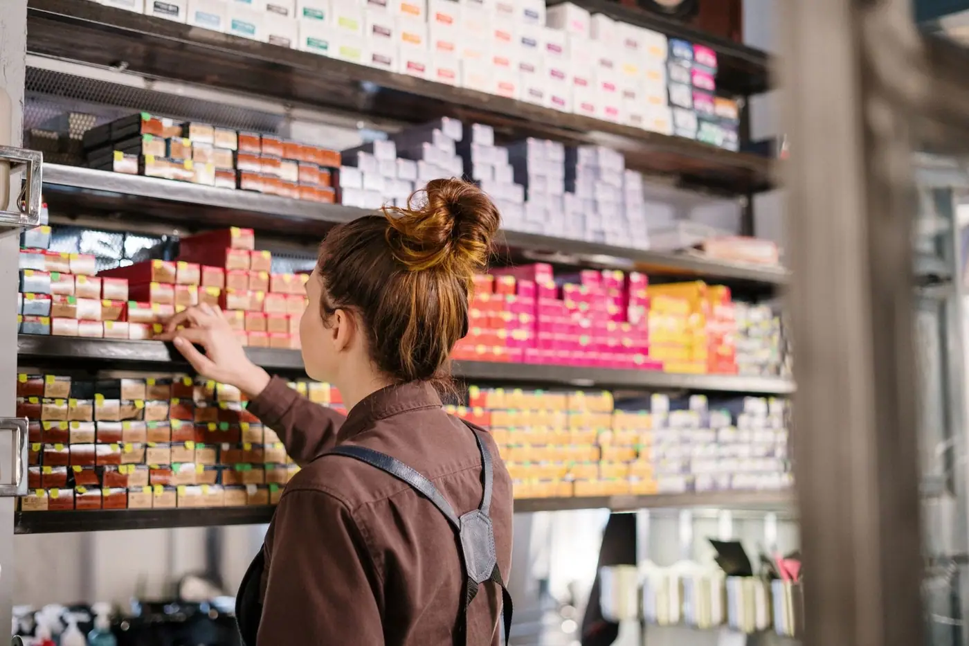 A hairdresser choosing a product from neatly organised salon shelves