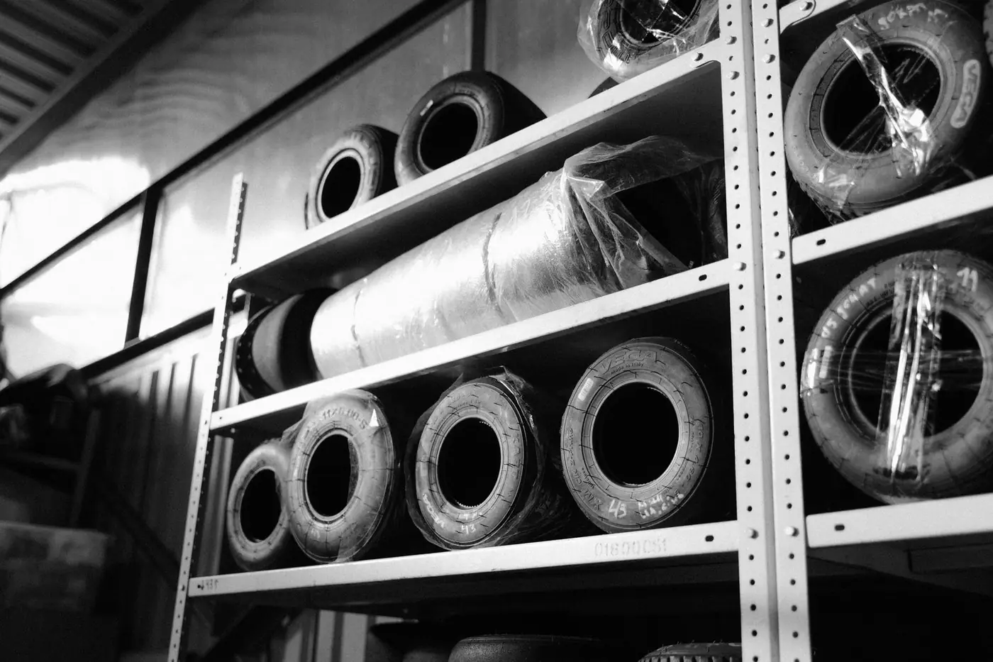 Black and white image of racing tyres stored on metal shelves