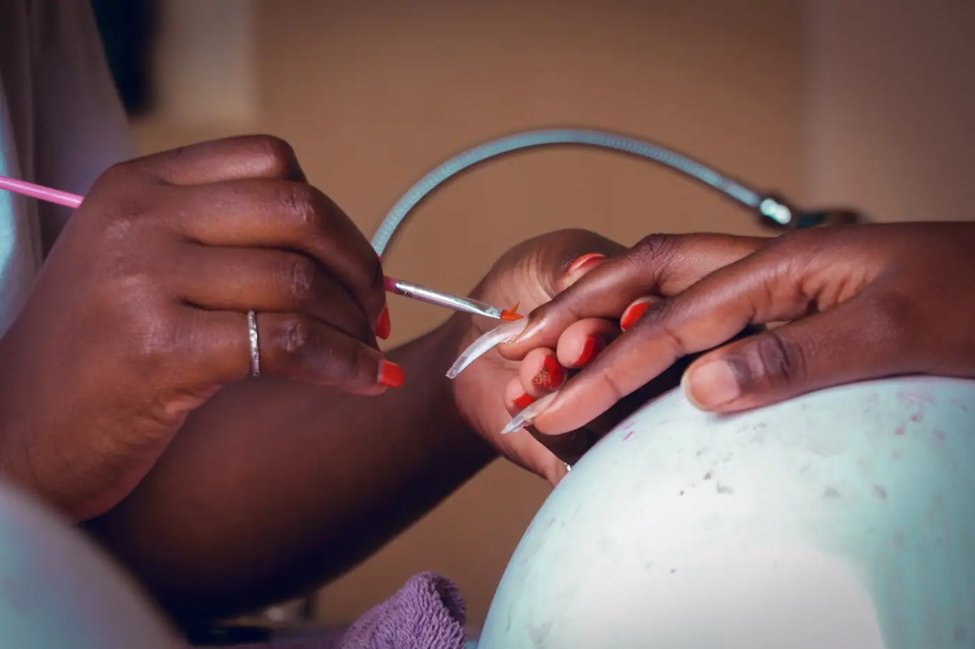 Close-up of a nail technician applying polish during a manicure