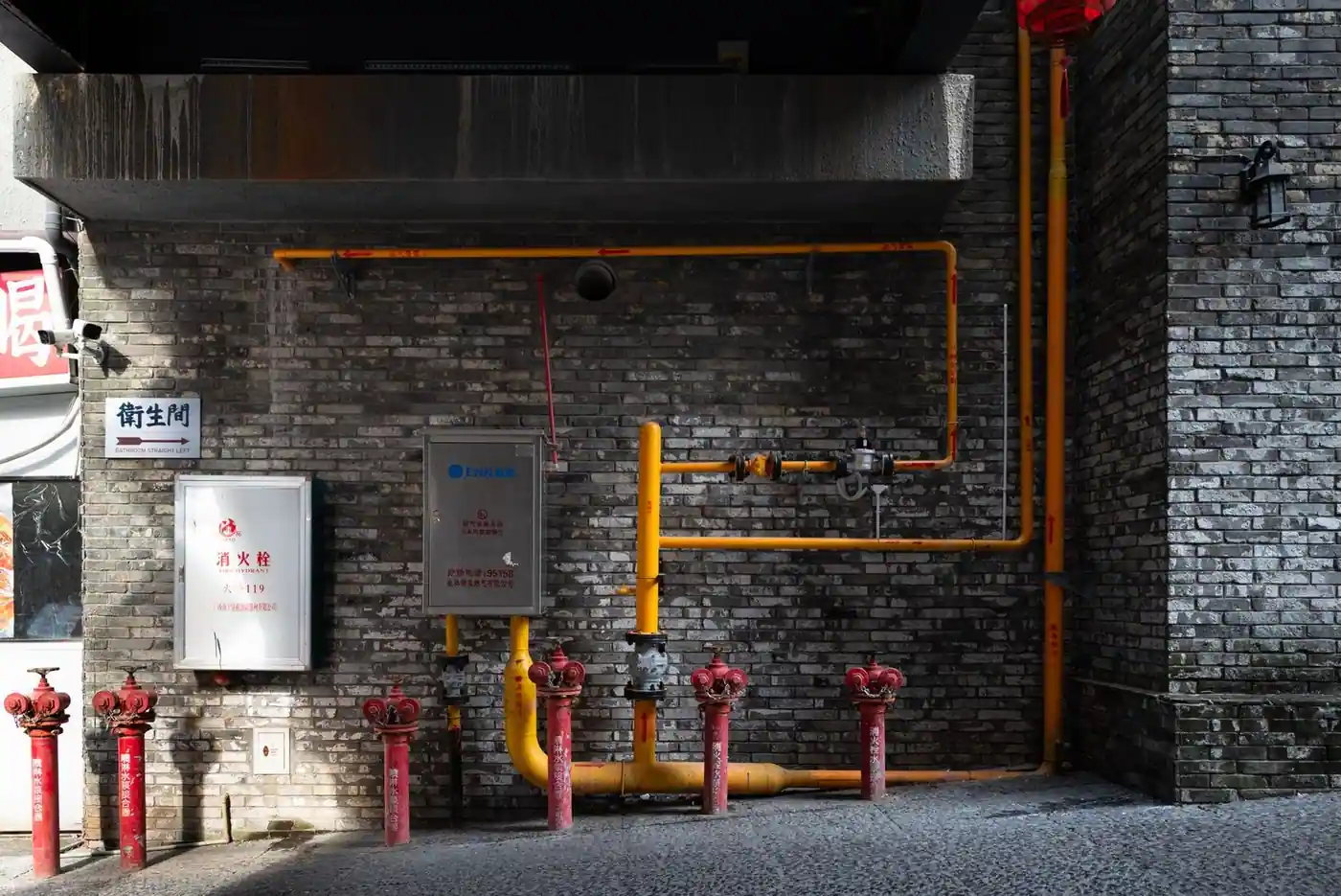 Brick wall with red hydrants and yellow piping in an urban alleyway