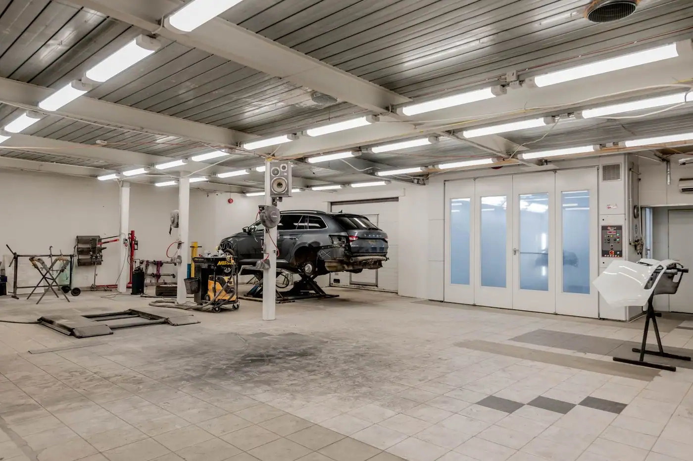 Interior of a modern car repair garage with a vehicle raised on a lift