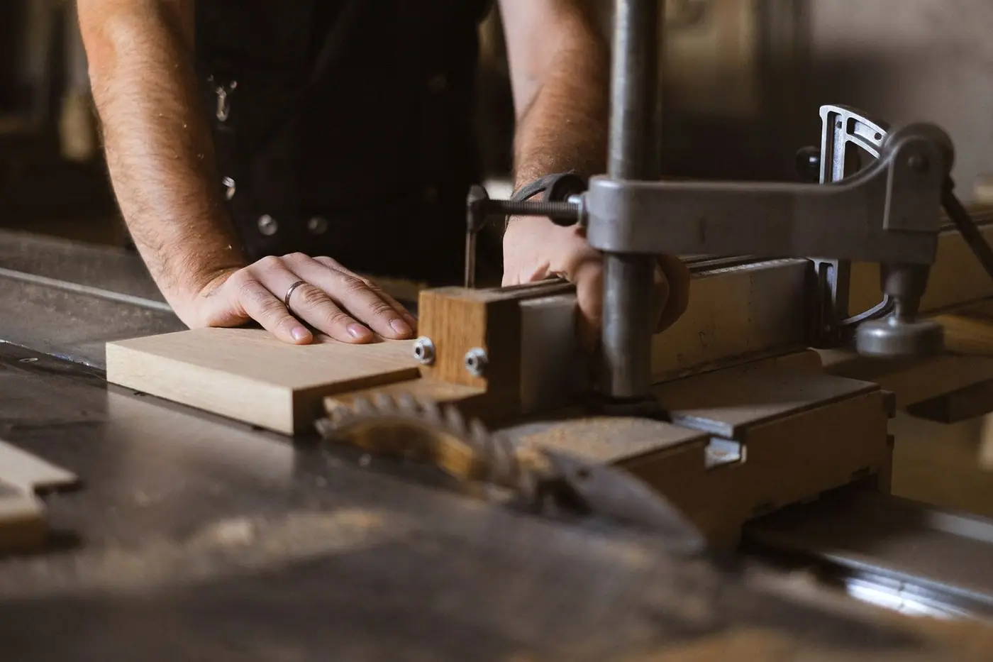 A craftsman cutting a wooden plank at a sawbench in a workshop