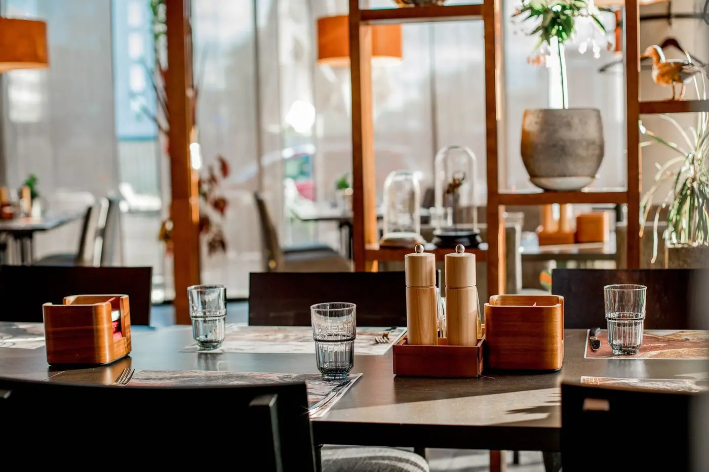 Elegant restaurant interior with sunlit tables and modern decor, set for dining