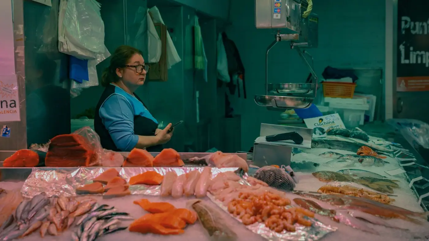 Female vendor at Valencia market showcasing fresh fish and seafood assortment