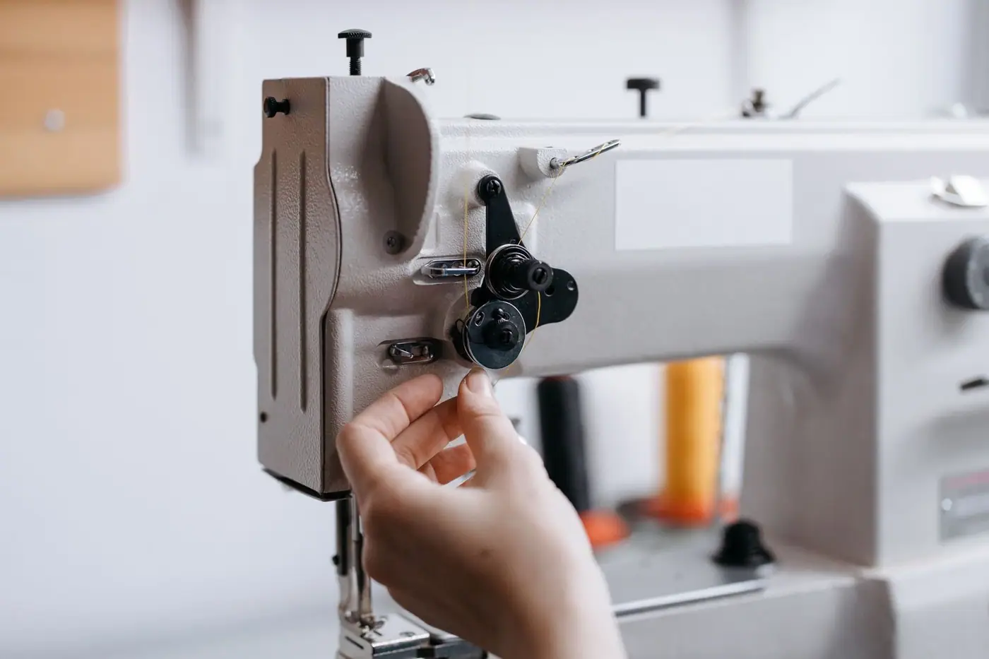 A hand guiding fabric through a sewing machine with fine thread