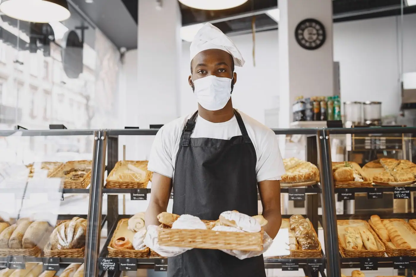 A baker presenting a tray of fresh bread in a modern bakery