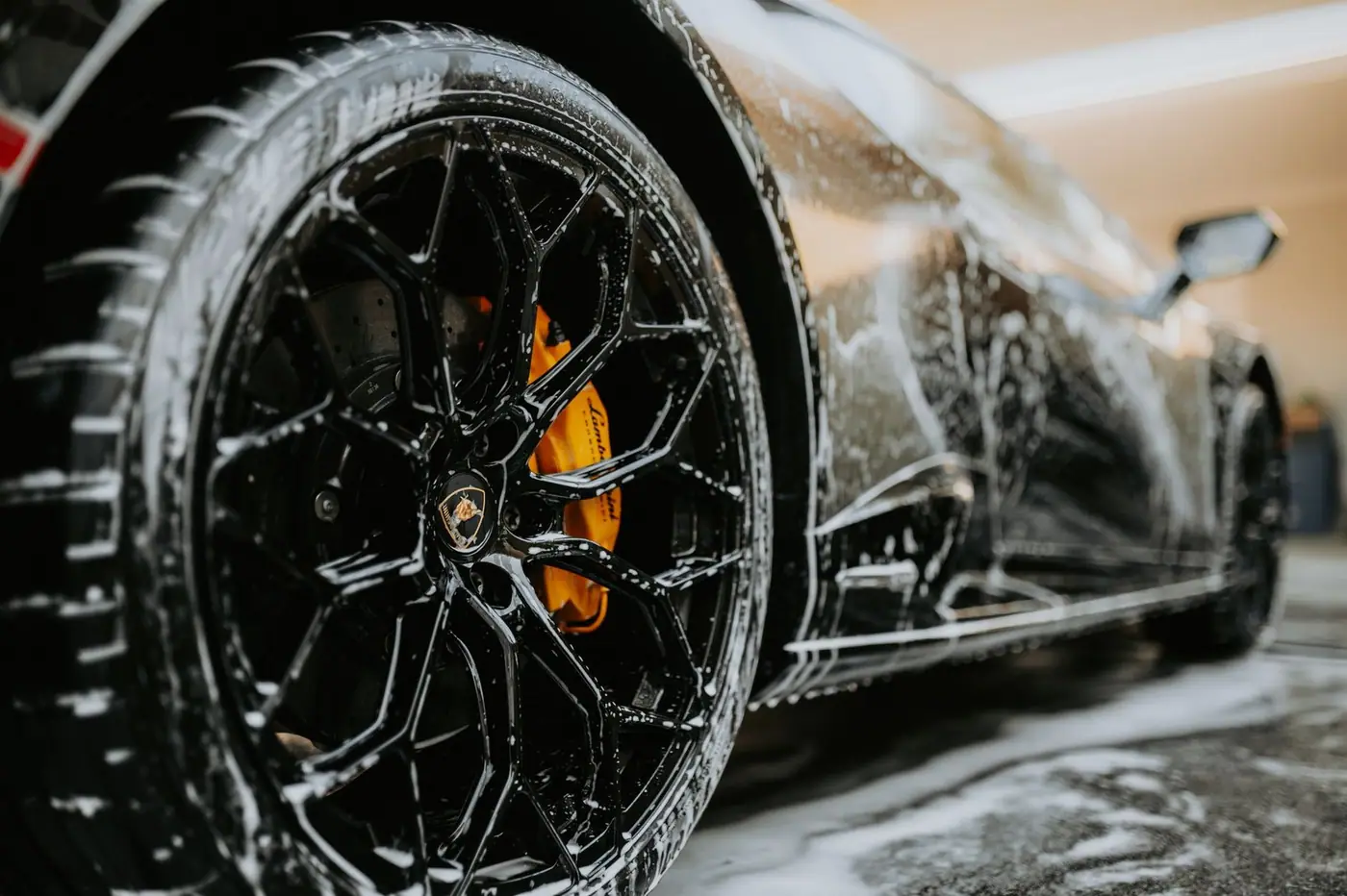 Close-up of a car wheel covered in soap suds during a car wash