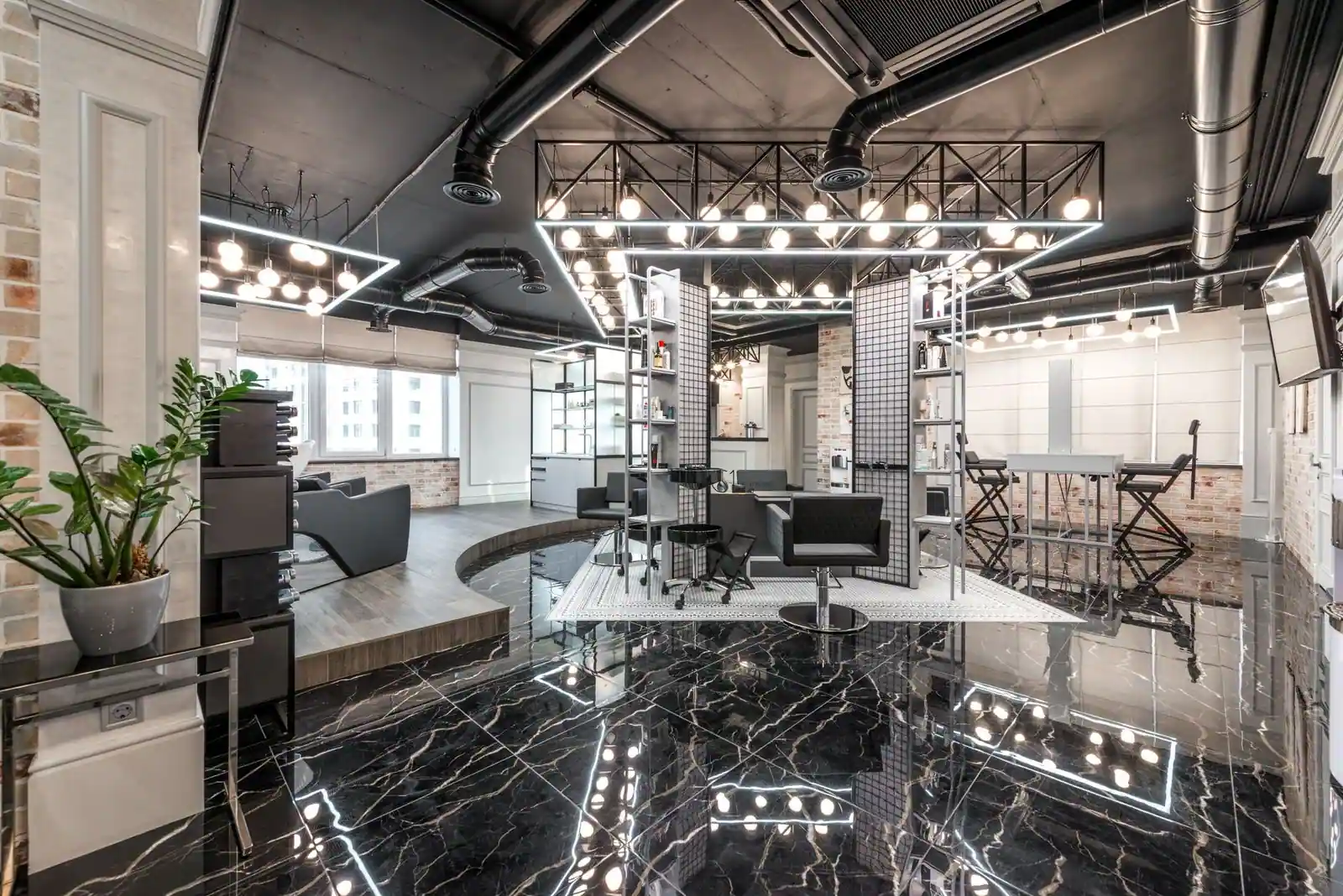 Black leather chairs placed in spacious stylish barbershop with bright glowing lamps and creative design with cosmetolog
