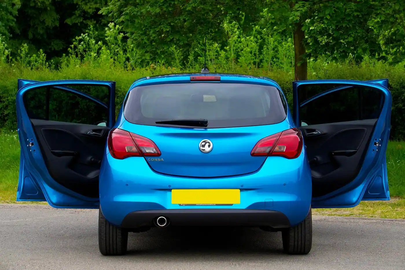 Rear view of a blue Vauxhall Corsa with its doors open on a street