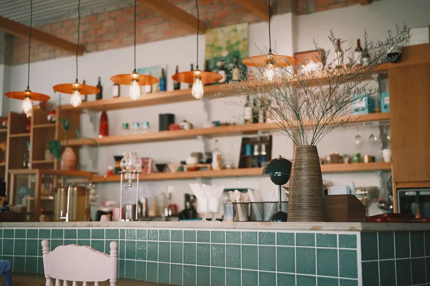 A stylish interior with pendant lights and decorative vases on a green tiled counter