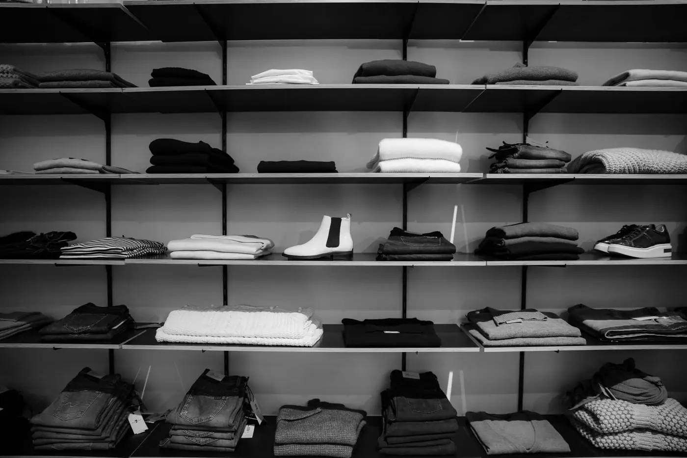 Neatly folded clothing and shoes displayed on shelves