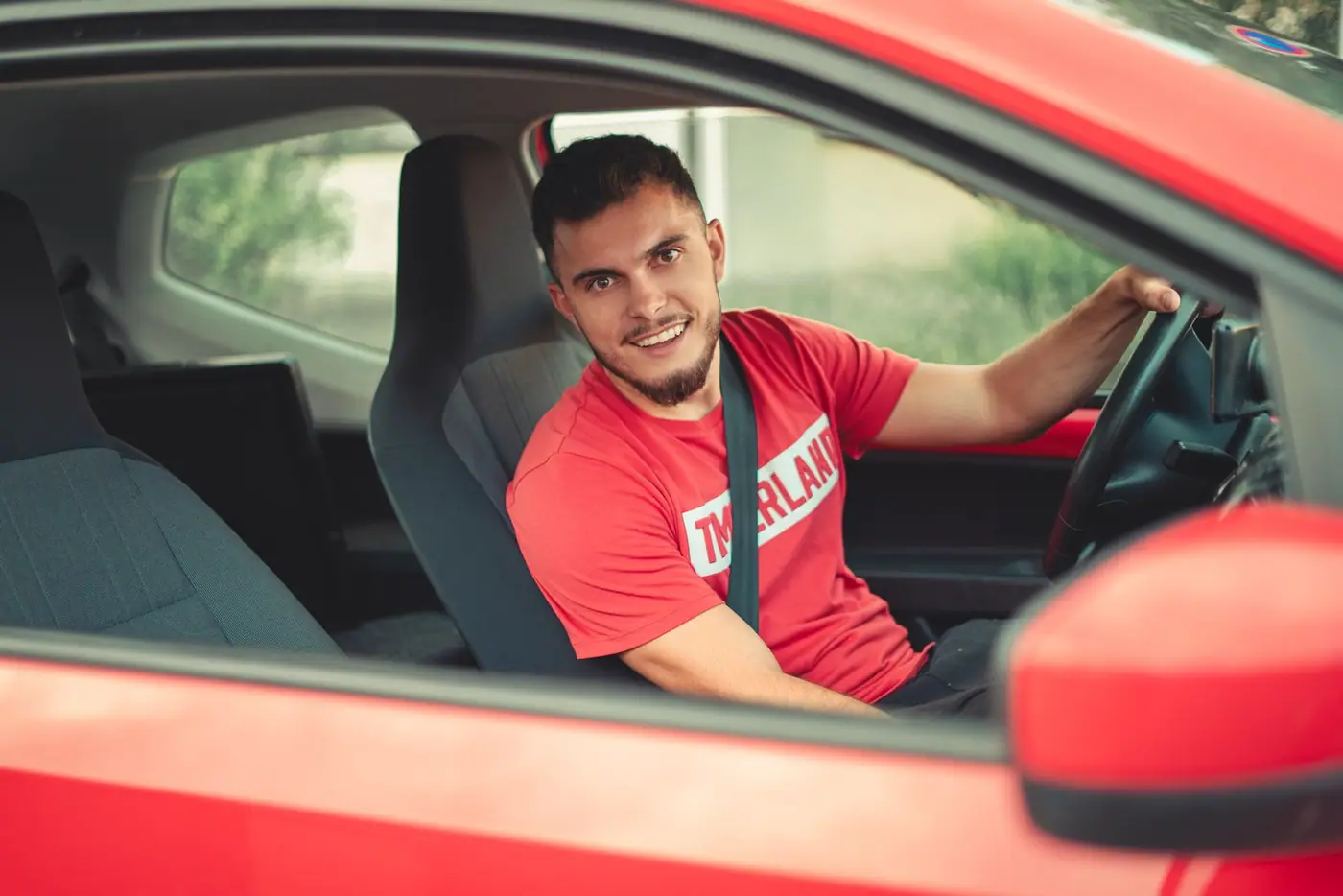 Smiling driver behind the wheel, wearing a seatbelt