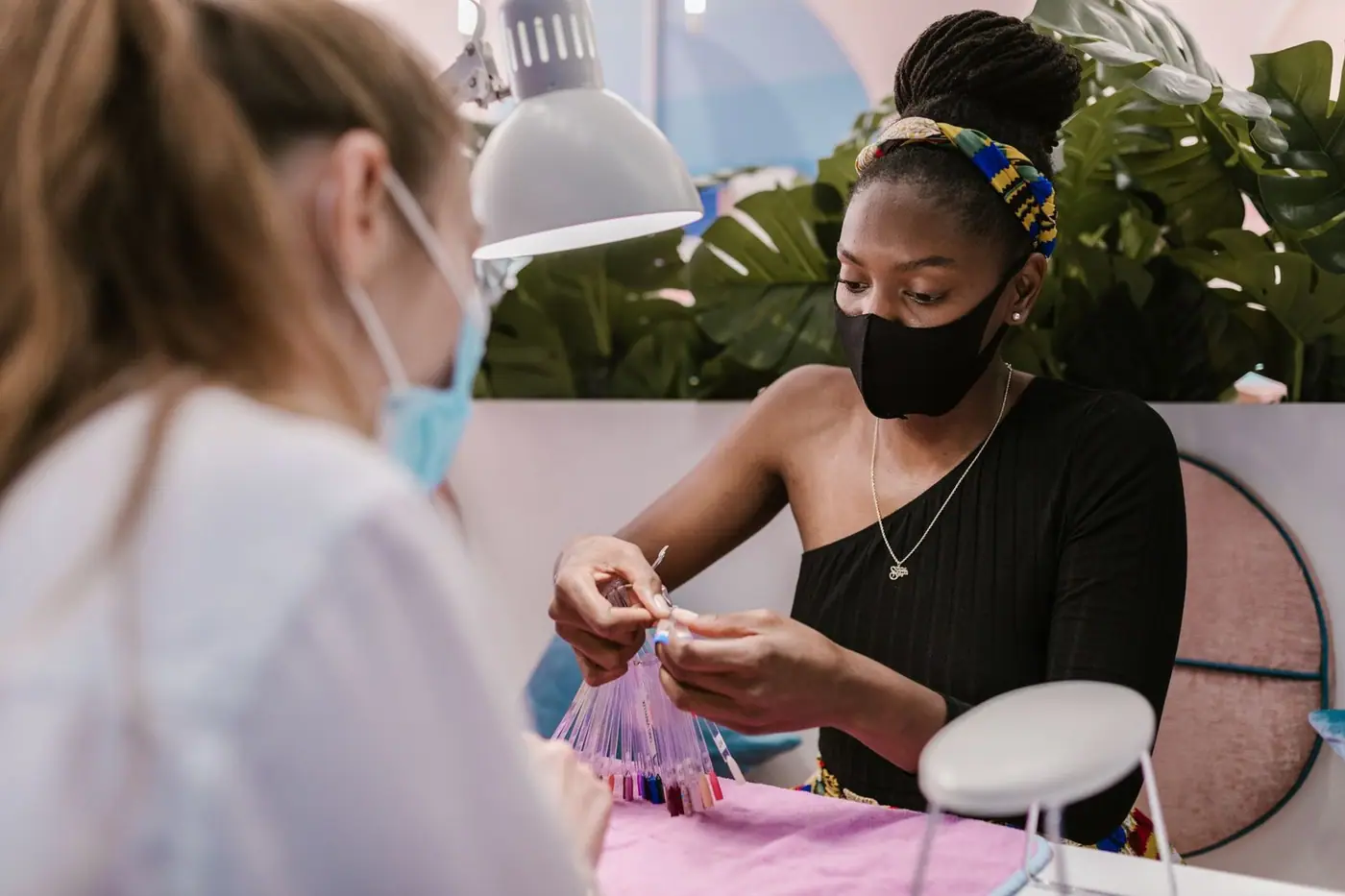 A nail technician and customer choosing nail polish colours in a modern salon