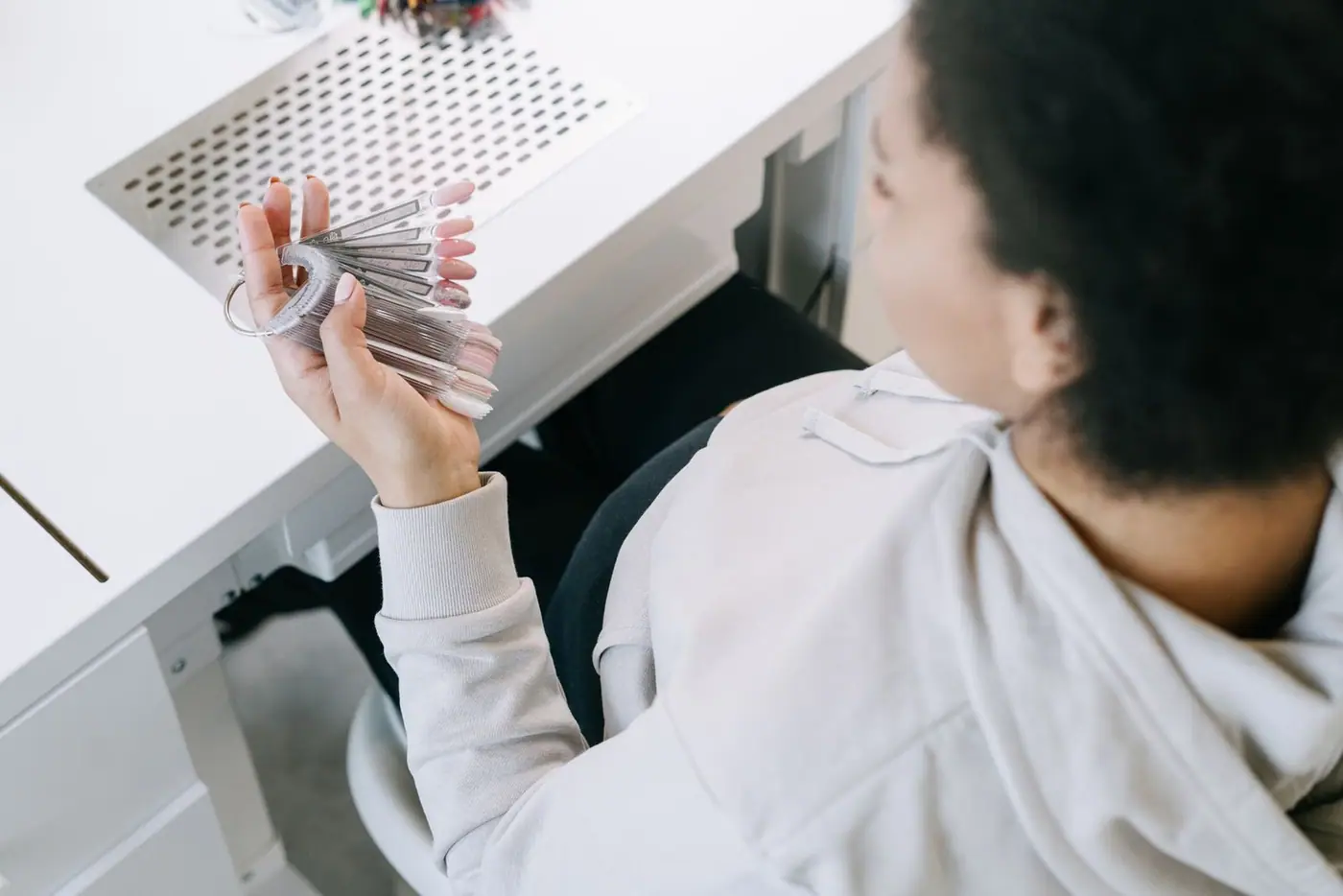 A woman holding nail polish samples, looking through manicure colour options