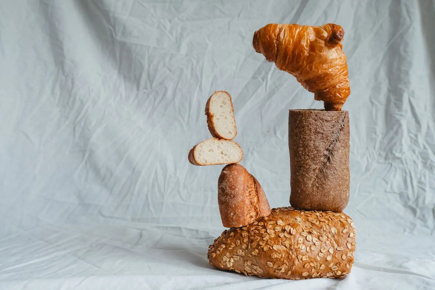 An artistic still life arrangement of various breads including a croissant