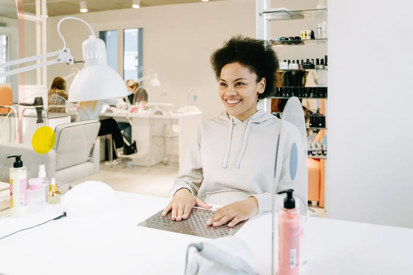 Smiling woman with afro hair having a manicure at a modern salon