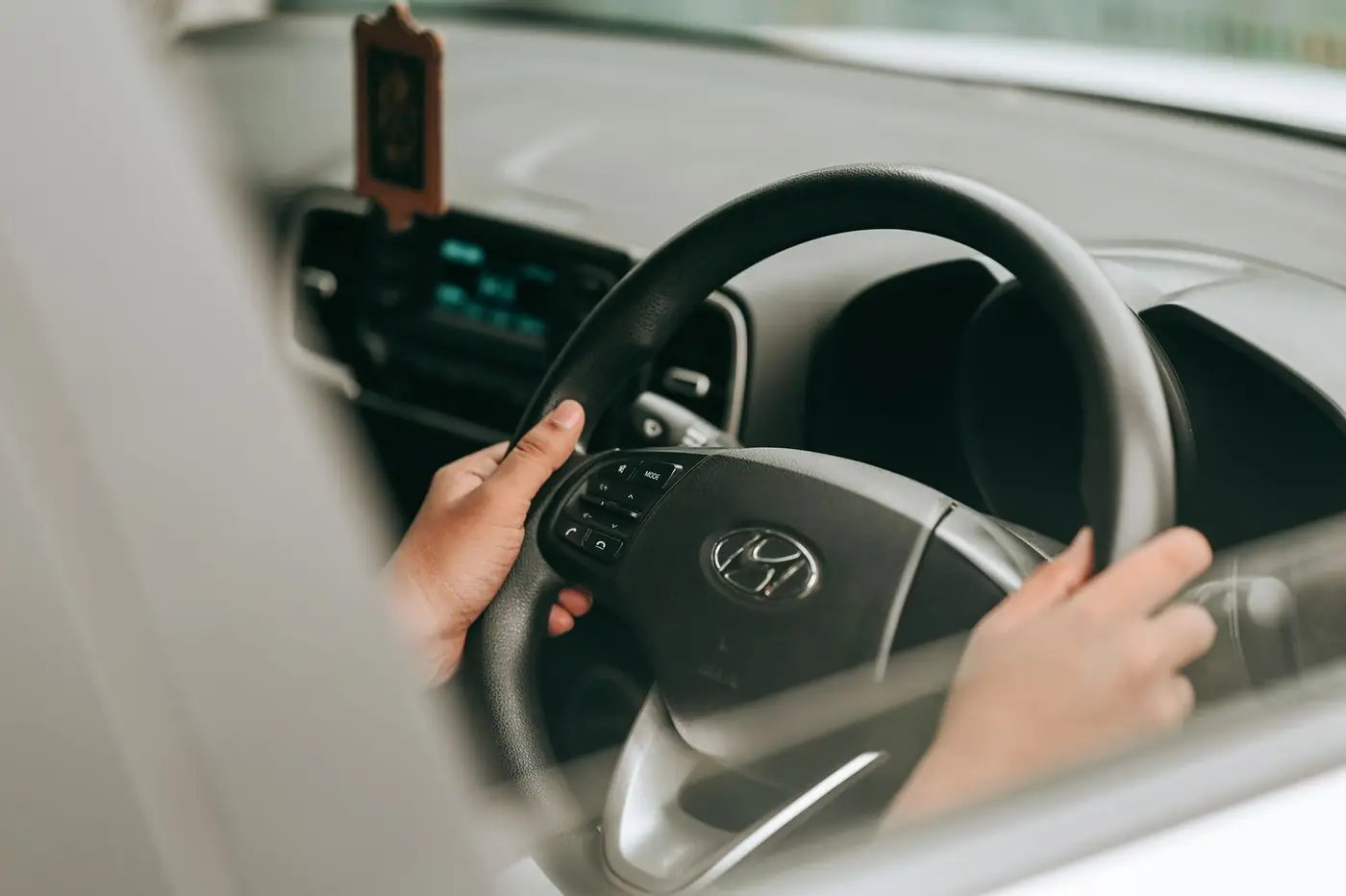 Close-up of hands holding the steering wheel inside a car.