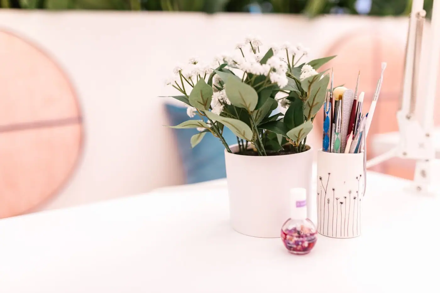 A white planter with green leaves and a nail polish bottle on a salon countertop